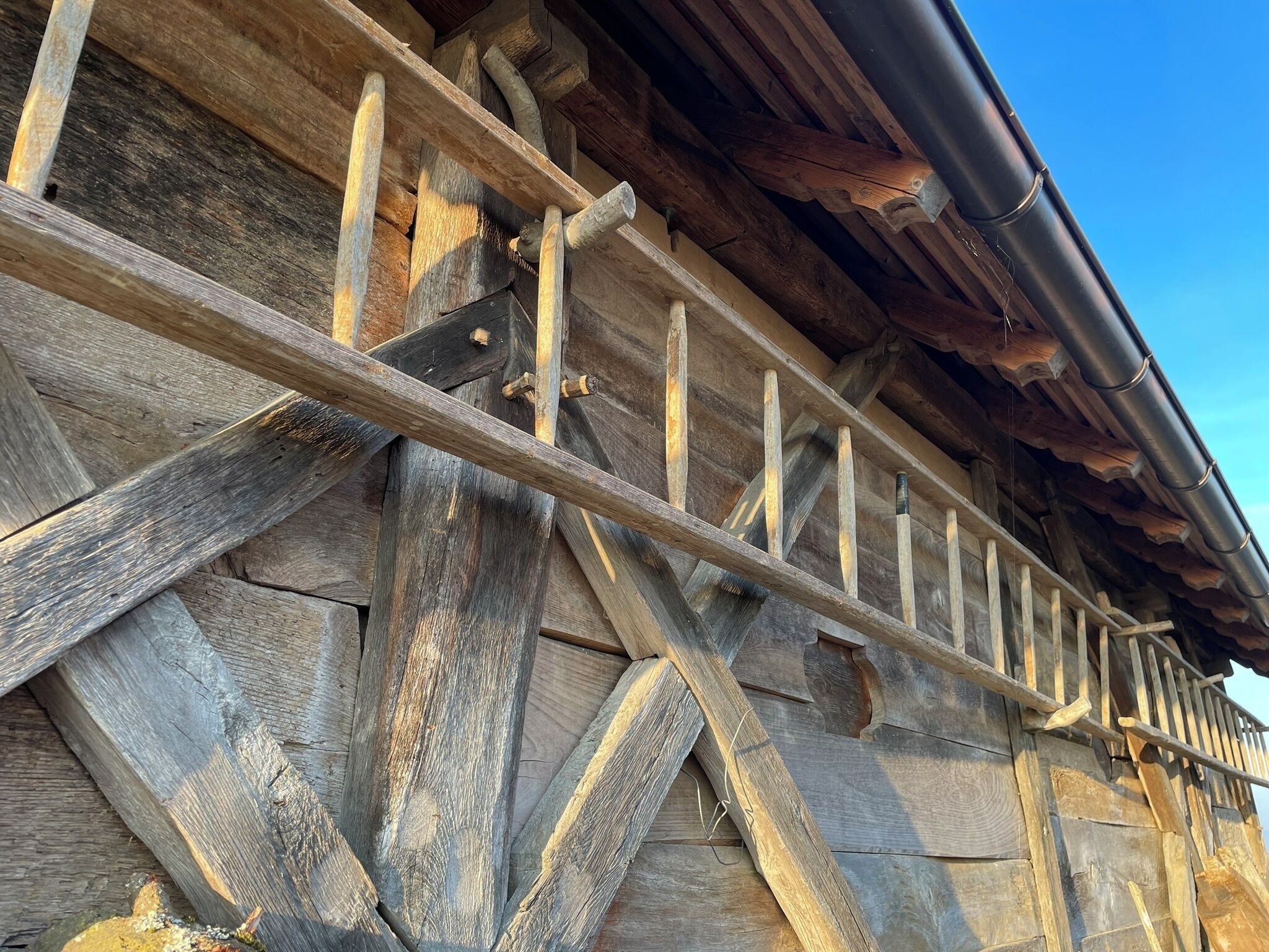 Una struttura in legno con tetto spiovente e grondaia in metallo.
