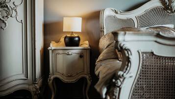 Una camera da letto con un letto classico, un comodino decorato e una lampada.