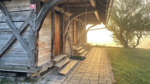 Un bâtiment rustique en bois, doté d’un porche et d’un chemin en briques menant à l’entrée.