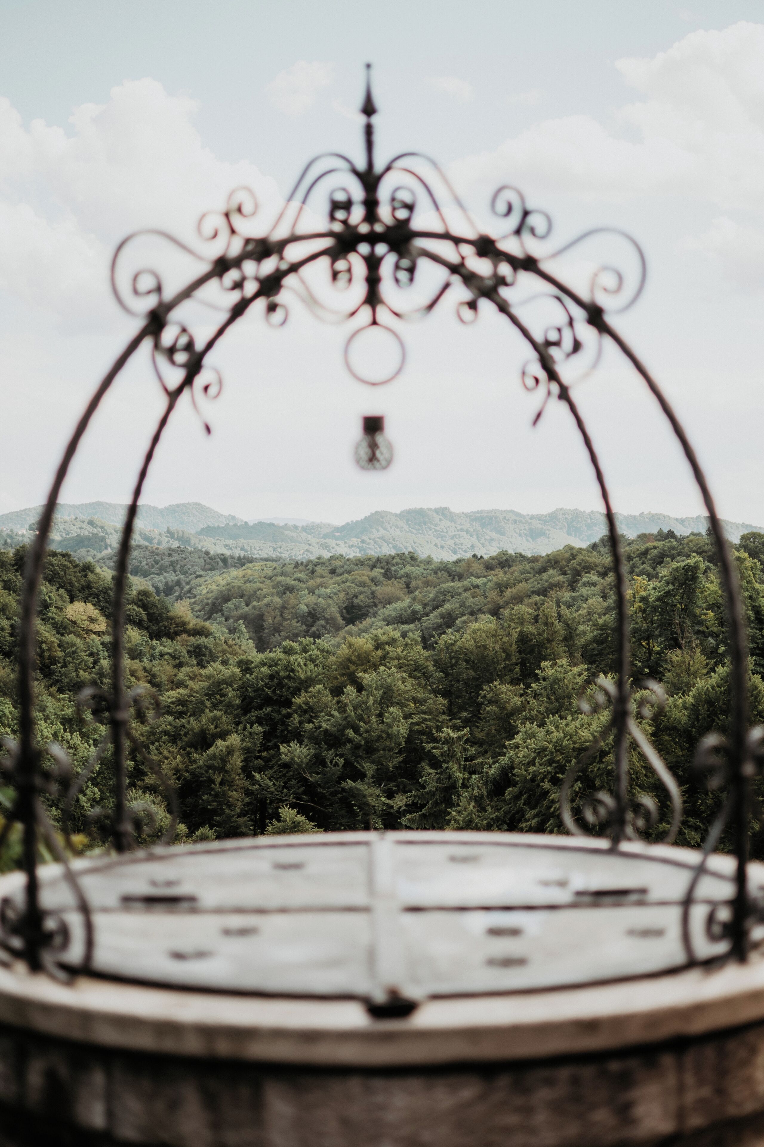 Un espacio circular con asientos al aire libre, barandilla de metal y vista a una cadena montañosa boscosa.