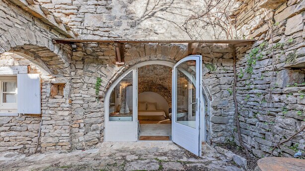 A stone-walled room with a bed, a window, and an open door leading to another room. - Cozy home in LE ROUET (LE ROUET)