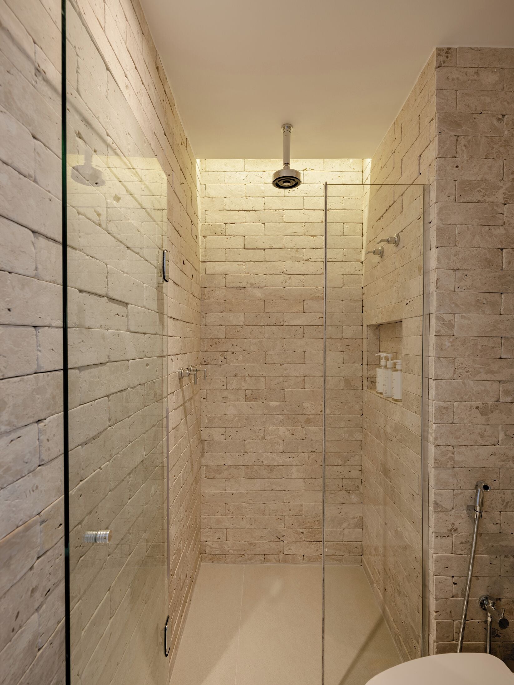 A modern shower room with a glass door, tiled walls, and a showerhead.