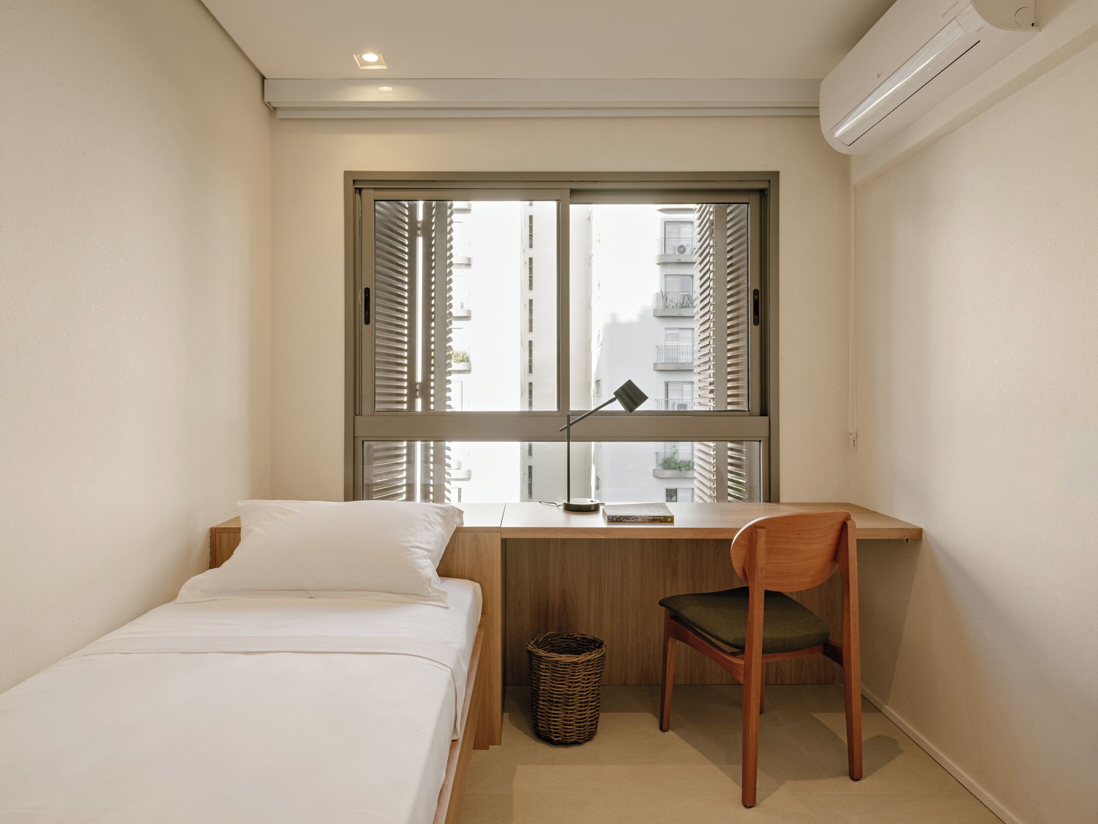 A small, neatly arranged bedroom with a bed, a desk, and a chair.