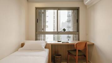 A small, neatly arranged bedroom with a bed, a desk, and a chair.