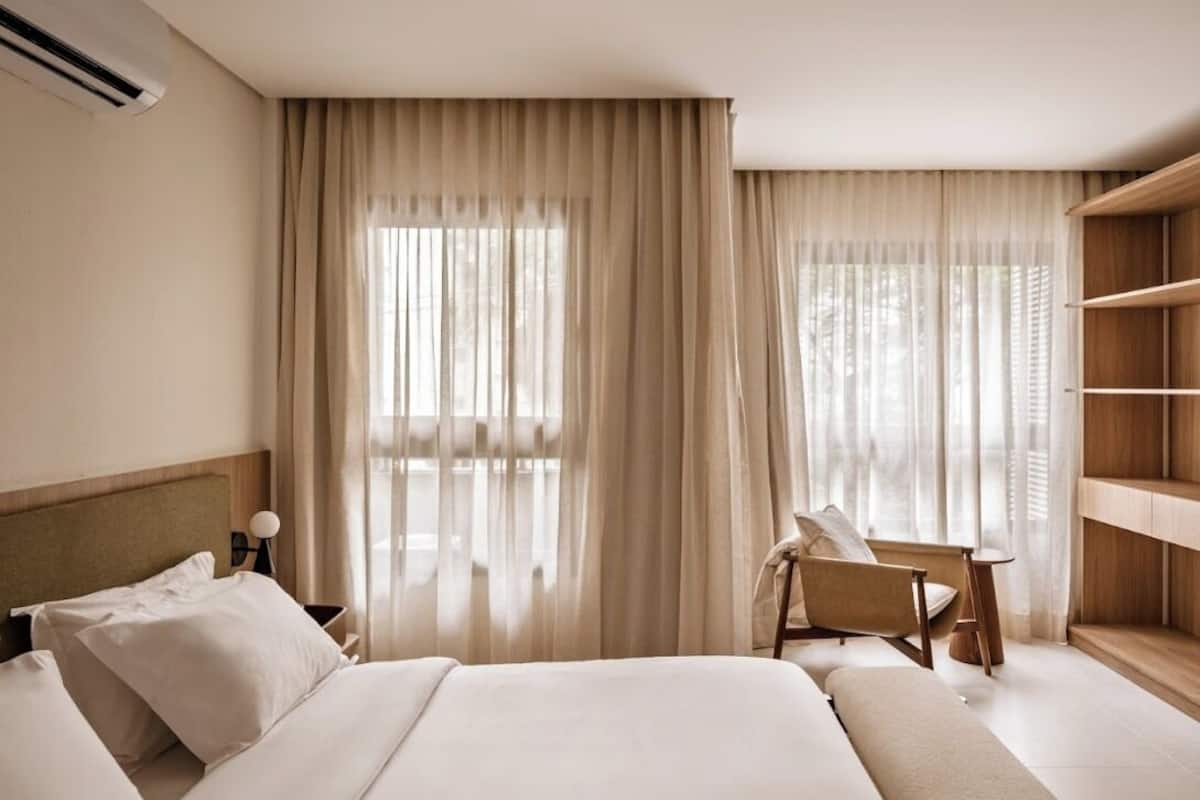 A hotel room with a large bed, a chair, a bedside table, and a wardrobe.