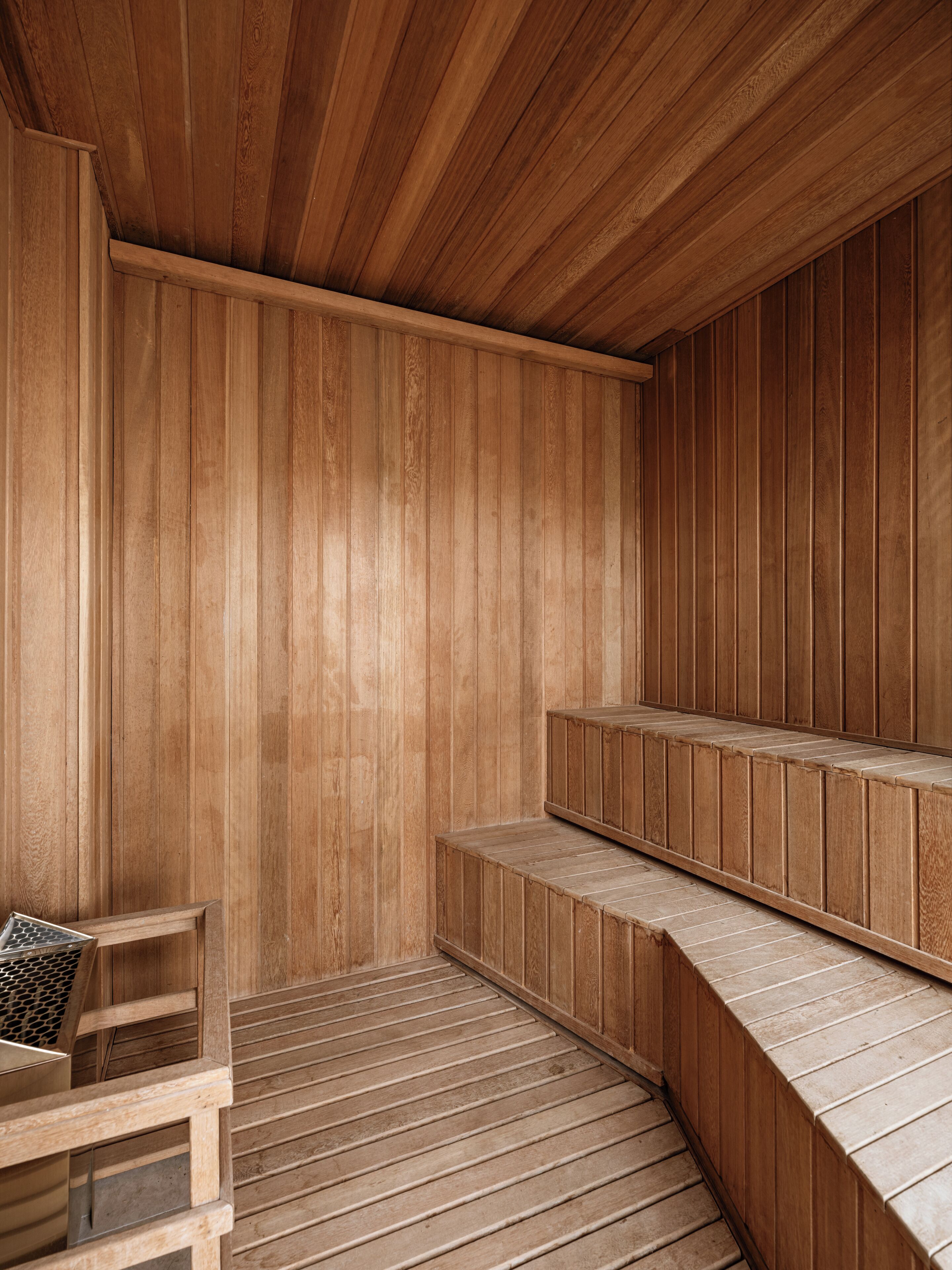 Eine Holzsauna mit Bänken, darunter eine Bank mit einem gemusterten Kissen.
