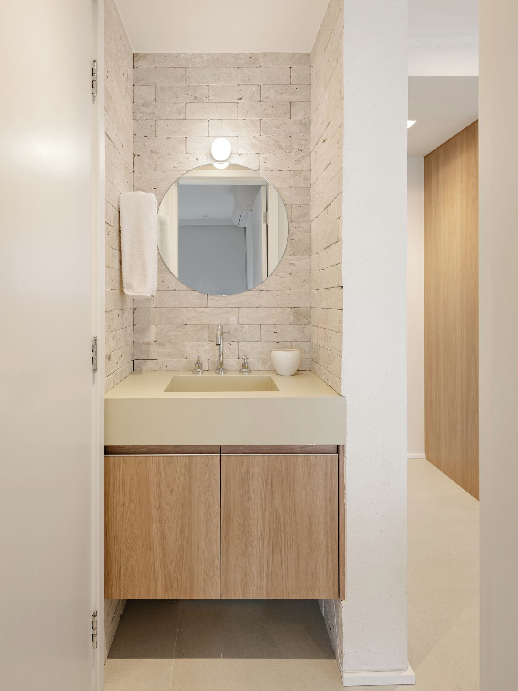 Un baño moderno con un lavamanos color beige, un espejo y una toalla colgada en la pared.