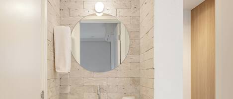 Un baño moderno con un lavamanos color beige, un espejo y una toalla colgada en la pared.