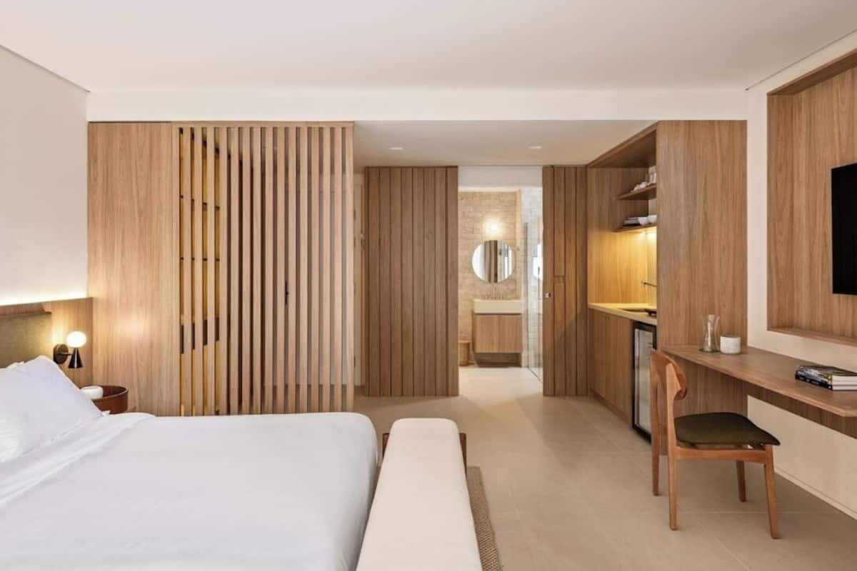 A modern hotel room with a large bed, a desk, and a television.
