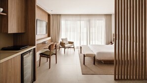 A modern hotel room with a bed, a desk with a laptop, a chair, and a television. - Aloe Vila Nova Conceição (São Paulo)