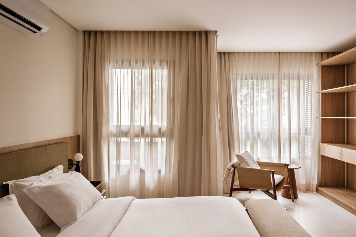 Una habitación de hotel con una cama grande, un escritorio y una estantería.