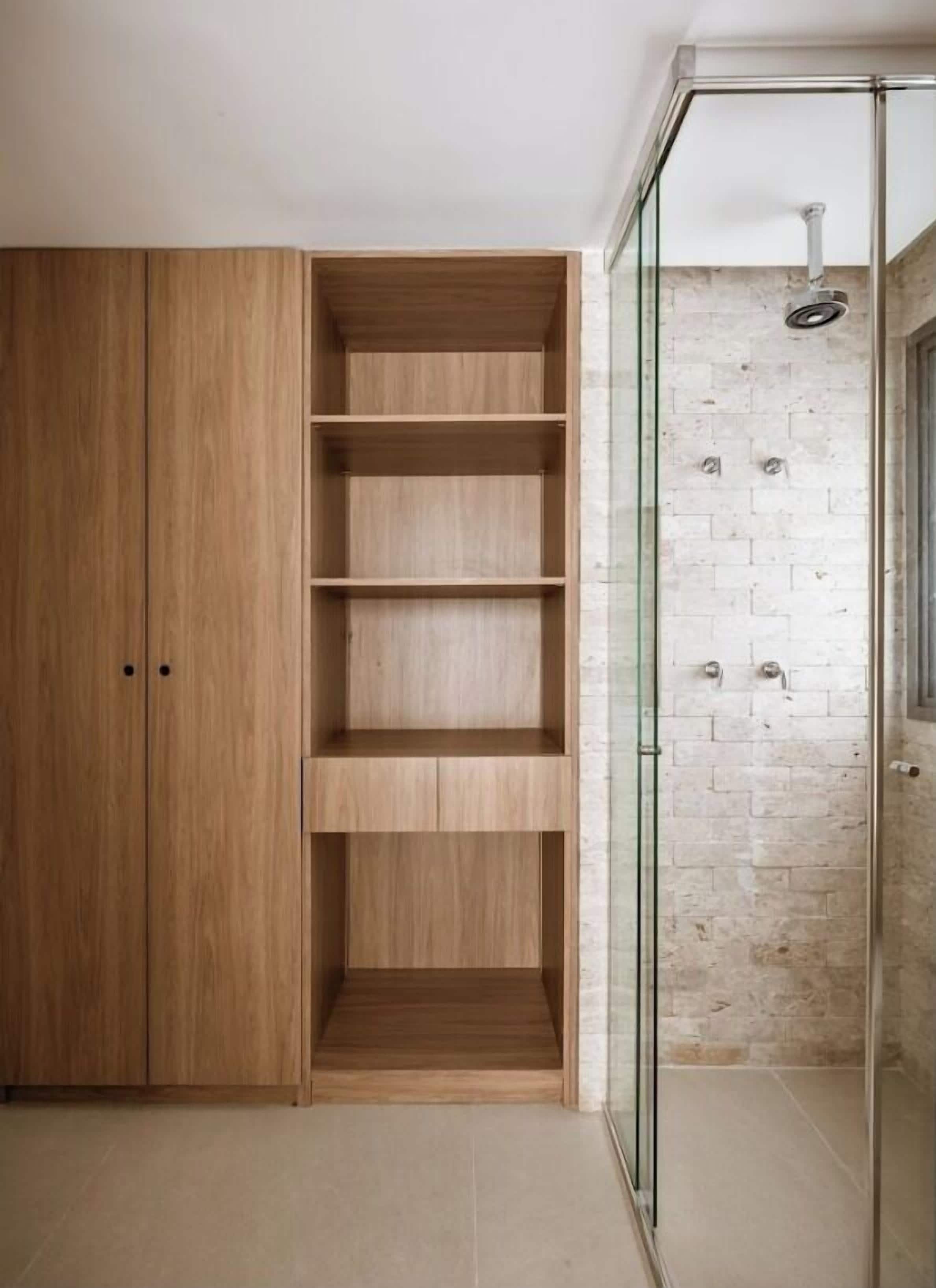 A modern bathroom with a wooden vanity, a glass shower enclosure, and a tiled floor.