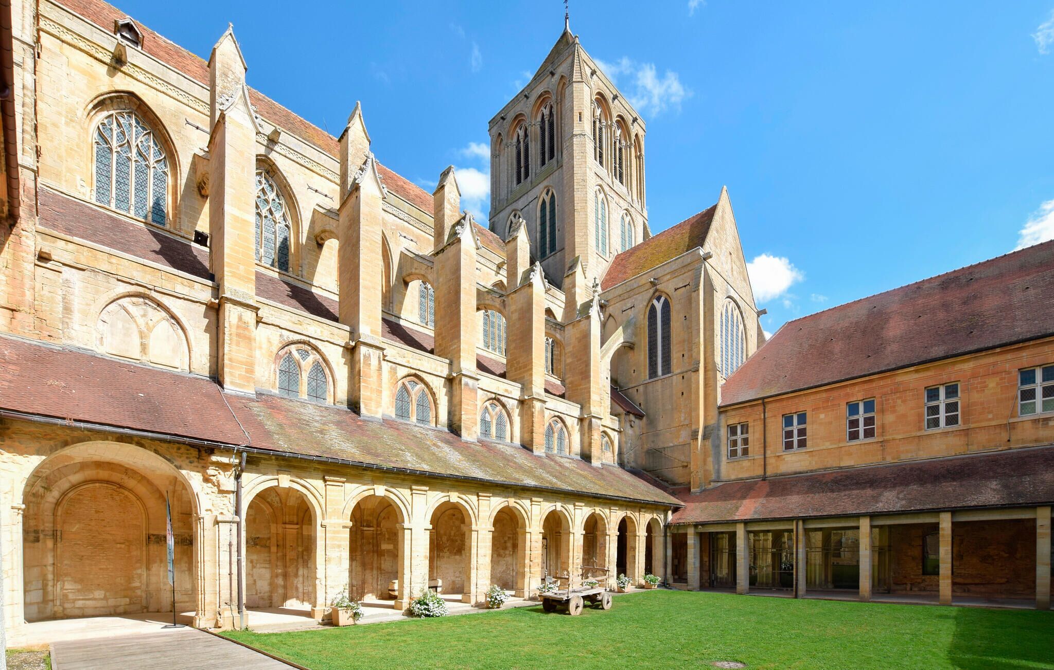 A courtyard with a historic building featuring arched walkways and a tower.