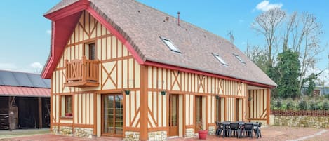 A traditional half-timbered building with a red roof, stone foundation, and a balcony with wooden railings.