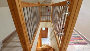 Eine Holztreppe mit Metallgeländer, die zu einer Zwischenebene mit einer Tür führt.