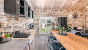 Une cuisine rustique avec des murs en pierre, des poutres en bois et une table à manger en bois.