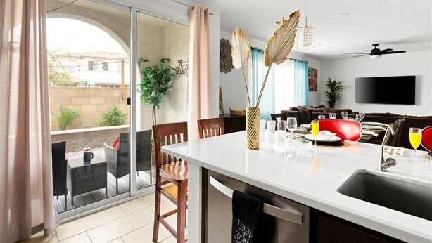 Una cocina moderna con comedor, televisor y puerta corrediza de vidrio a un balcón.
