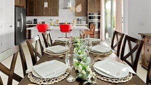 Una cocina moderna con armarios de madera, un refrigerador de acero inoxidable y un comedor con una mesa dispuesta para seis comensales.
