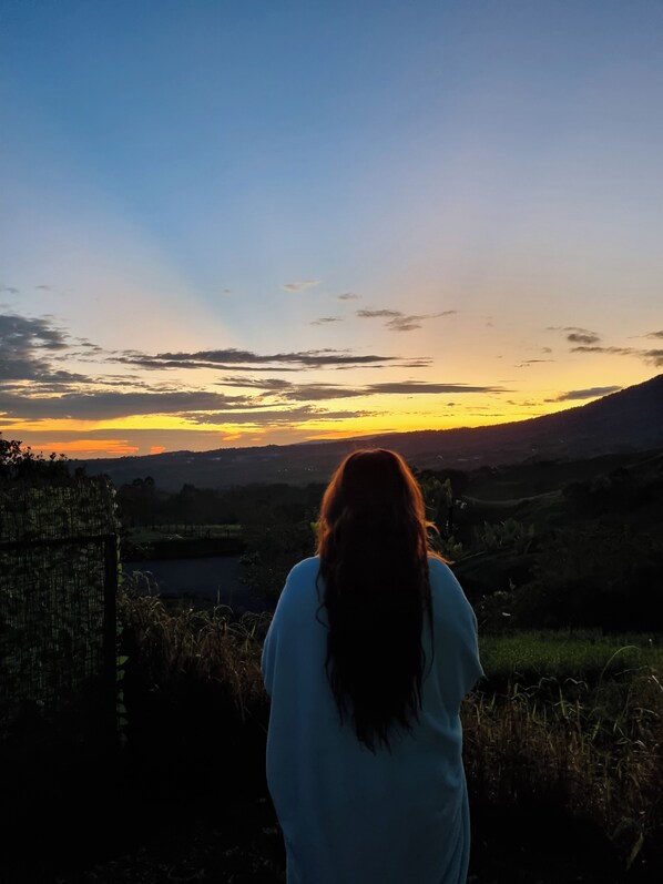 Una persona observa una puesta de sol sobre un paisaje montañoso.