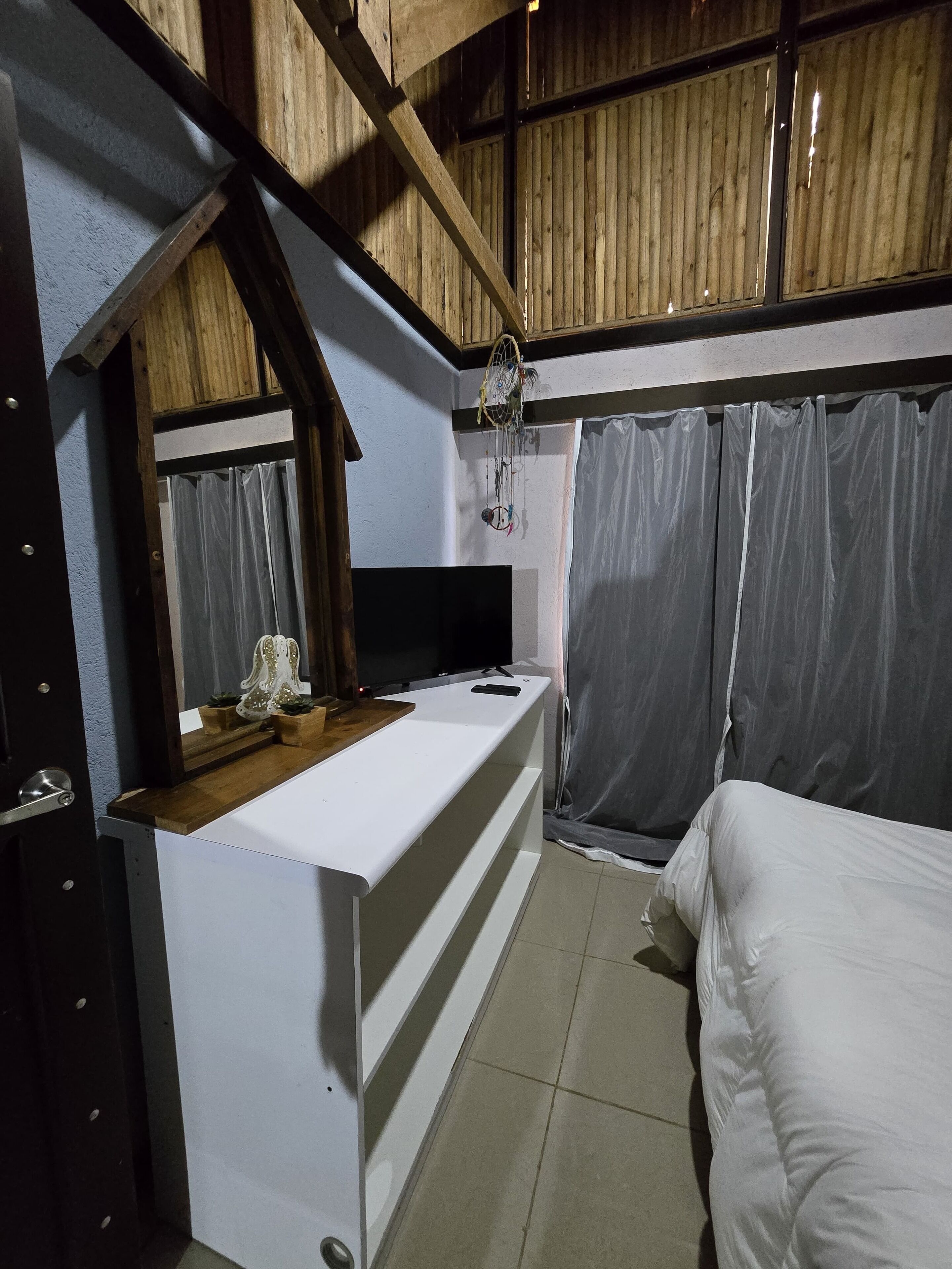 A bedroom with a bed, a small desk with a mirror, and a TV.