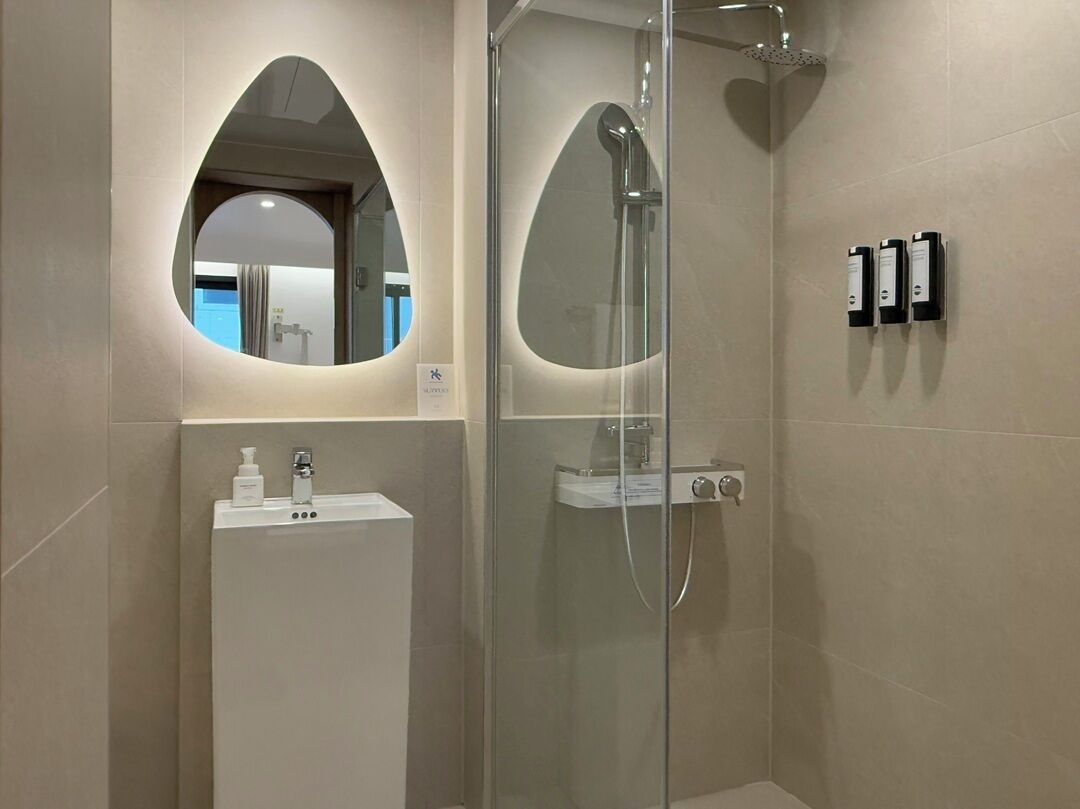 A modern bathroom with a glass-enclosed shower, a vanity with a mirror, and a sink.
