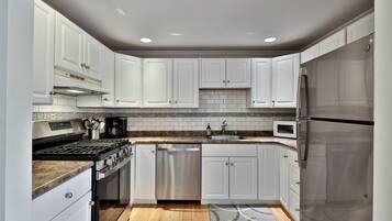 A modern kitchen with white cabinets, stainless steel appliances, and a patterned rug.