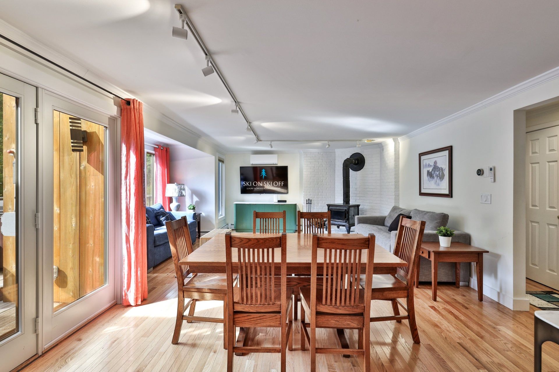 Un salón amplio con una mesa de comedor y sillas, un sofá y un televisor montado en la pared.