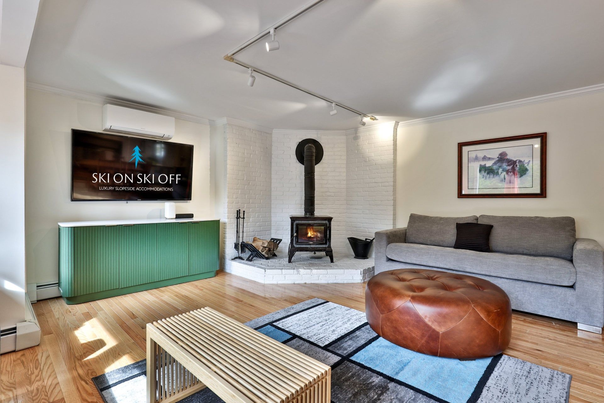 A modern living room with a fireplace, a green accent wall, a grey sofa, and a television displaying an advertisement.