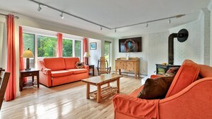 A living room with a sofa, a wooden coffee table, a TV mounted on the wall, and a fireplace. - Trailside Village #1: Slopeside 1BR w/ Hot Tub and Sauna. Ski In/Out with Discounted Ski Rentals (Killington)