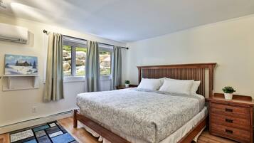 A bedroom with a wooden bed, a nightstand, a small potted plant, and a painting on the wall.