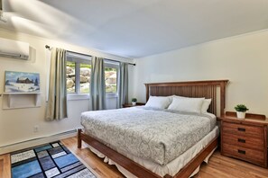 A bedroom with a wooden bed, a nightstand, a small potted plant, and a painting on the wall.