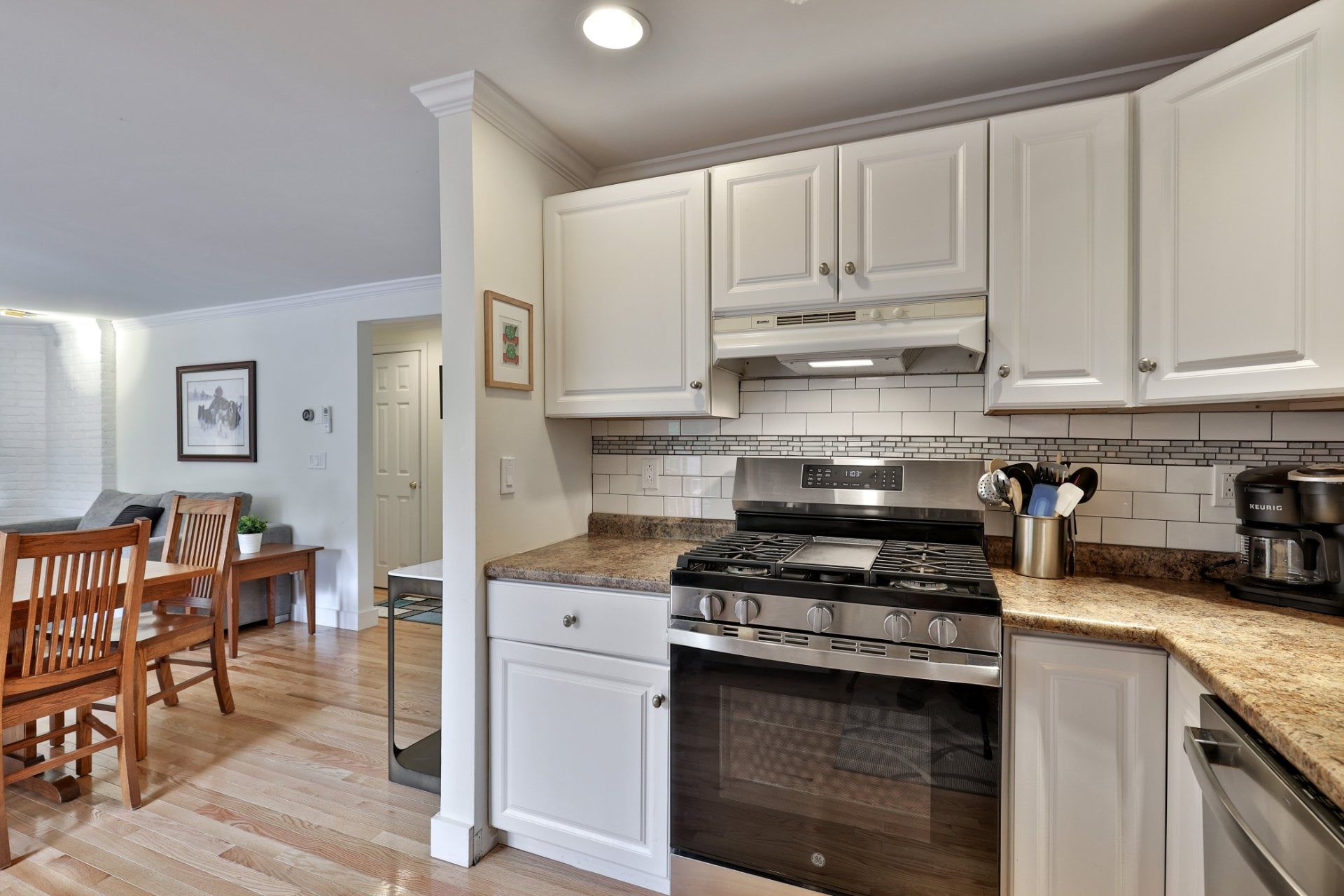 A modern kitchen with white cabinets, a stainless steel stove, and a granite countertop.