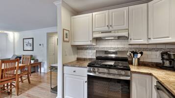 A modern kitchen with white cabinets, a stainless steel stove, and a granite countertop.