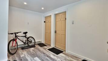 Un couloir avec deux portes, un vélo et un paillasson à l’entrée.