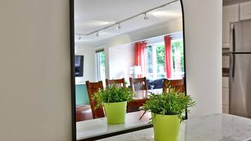 A kitchen with a white refrigerator, a dining area with chairs and a table, and two potted plants on the counter.