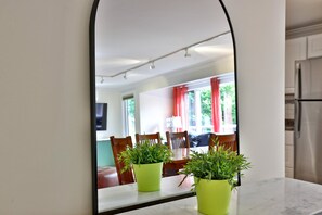 A kitchen with a white refrigerator, a dining area with chairs and a table, and two potted plants on the counter.