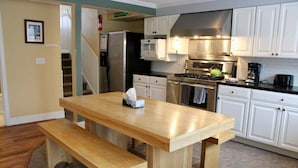 A kitchen with white cabinets, a wooden table, a bench, a refrigerator, a microwave, an oven, and a gas stove. - Trailside Village 3: Gas Fireplace, Hot Tub and Great Eastern Access (Killington)