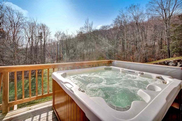 Private deck hot tub with wooded views and railing.