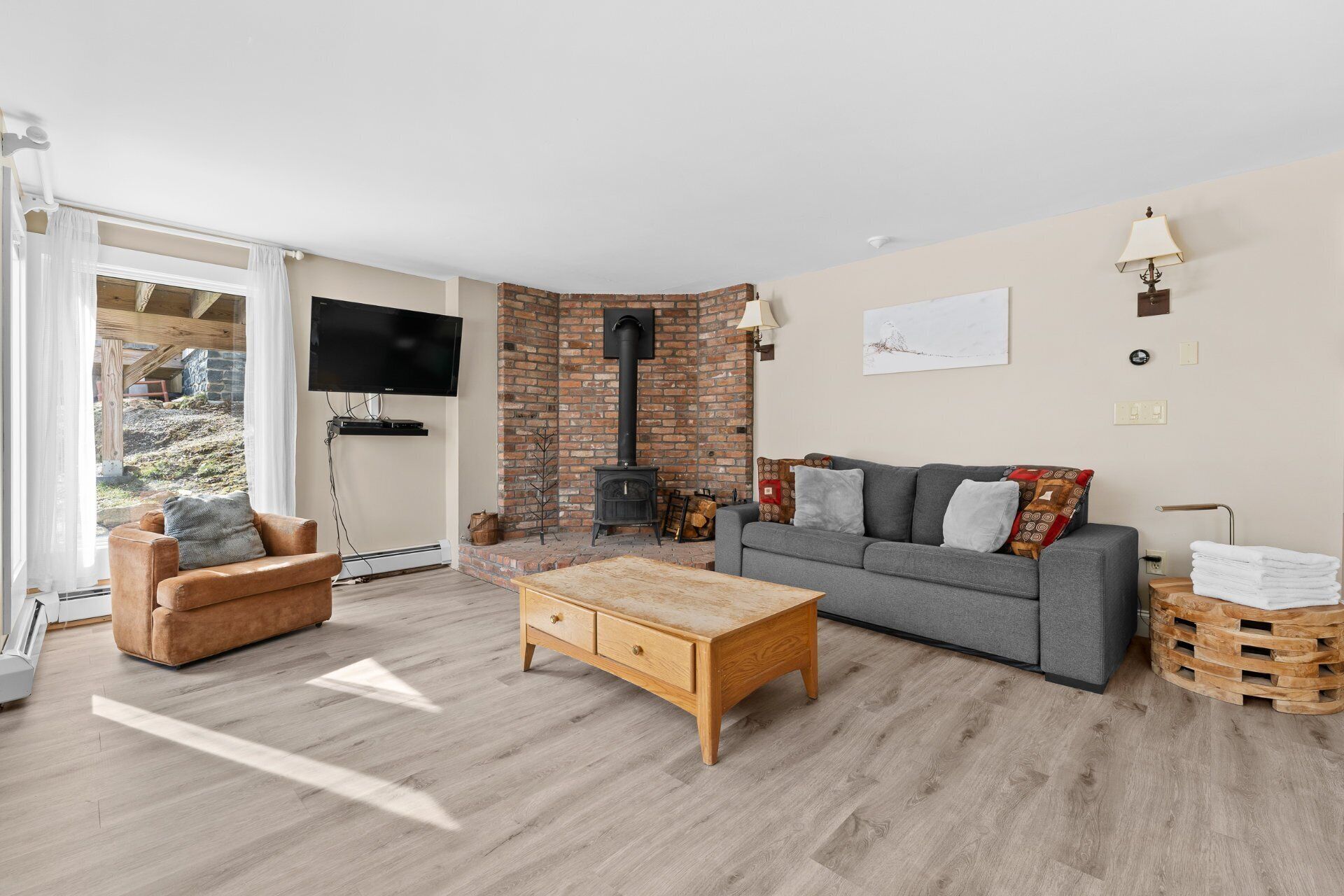 A cozy living room with a sofa, a wooden coffee table, and a fireplace.