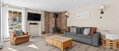 A cozy living room with a sofa, a wooden coffee table, and a fireplace.
