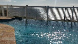 A swimming pool with a white fence and a clear view of the ocean. - Surfside Beach Condo in wonderful Aguada, PR (Aguada)
