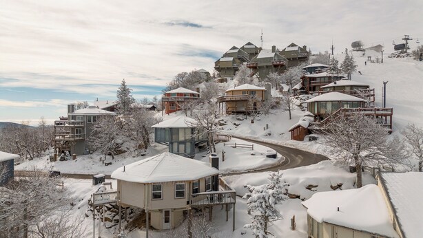 A snow-covered residential area with houses on a hillside, featuring a mix of single and multi-story buildings, some with balconies. - Classic | Ski-in/Out | Views | PetFriendly | 2BR (Beech Mountain)
