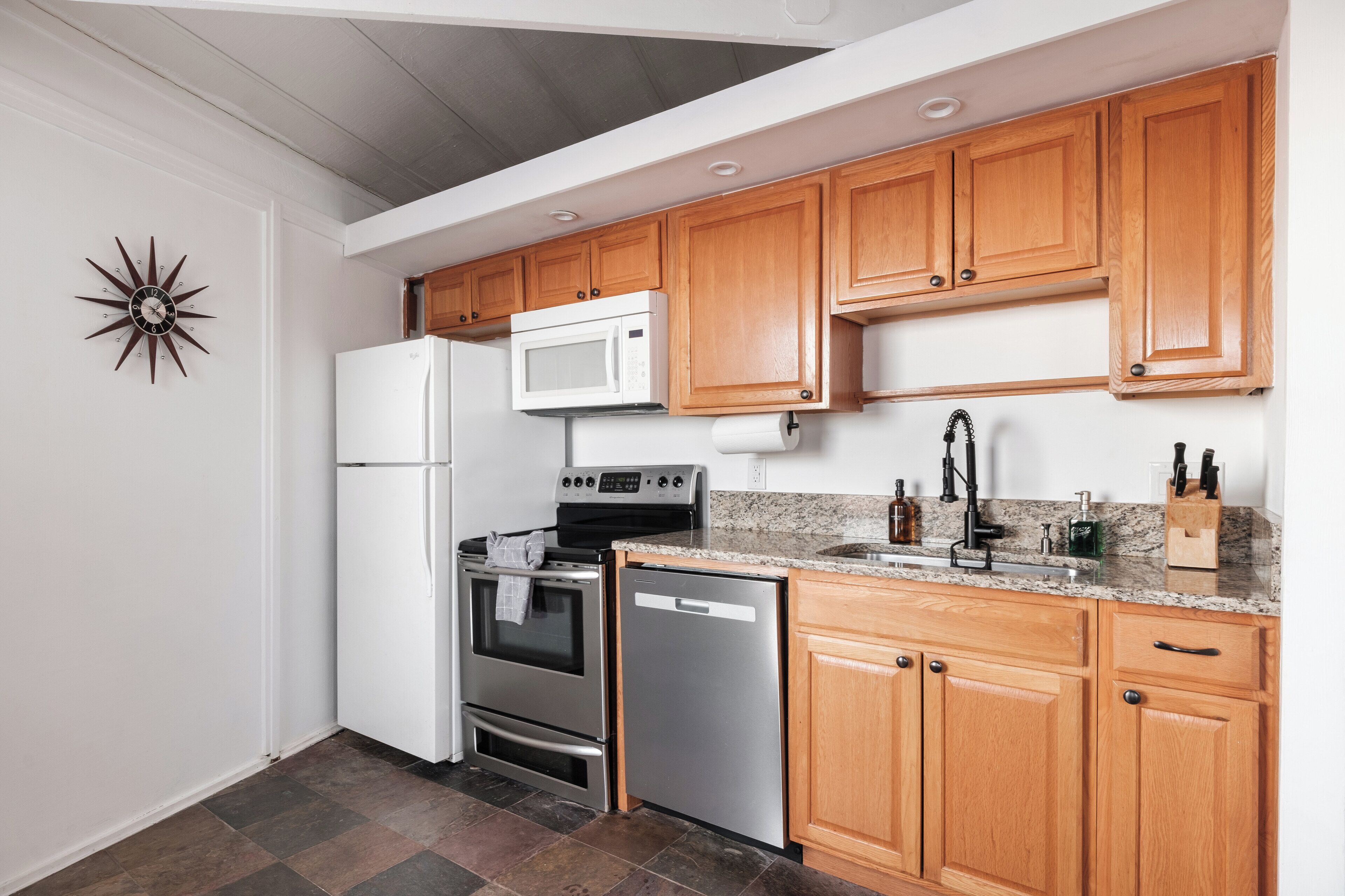 A kitchen with wooden cabinets, a stainless steel refrigerator, a microwave, an oven, and a dishwasher.