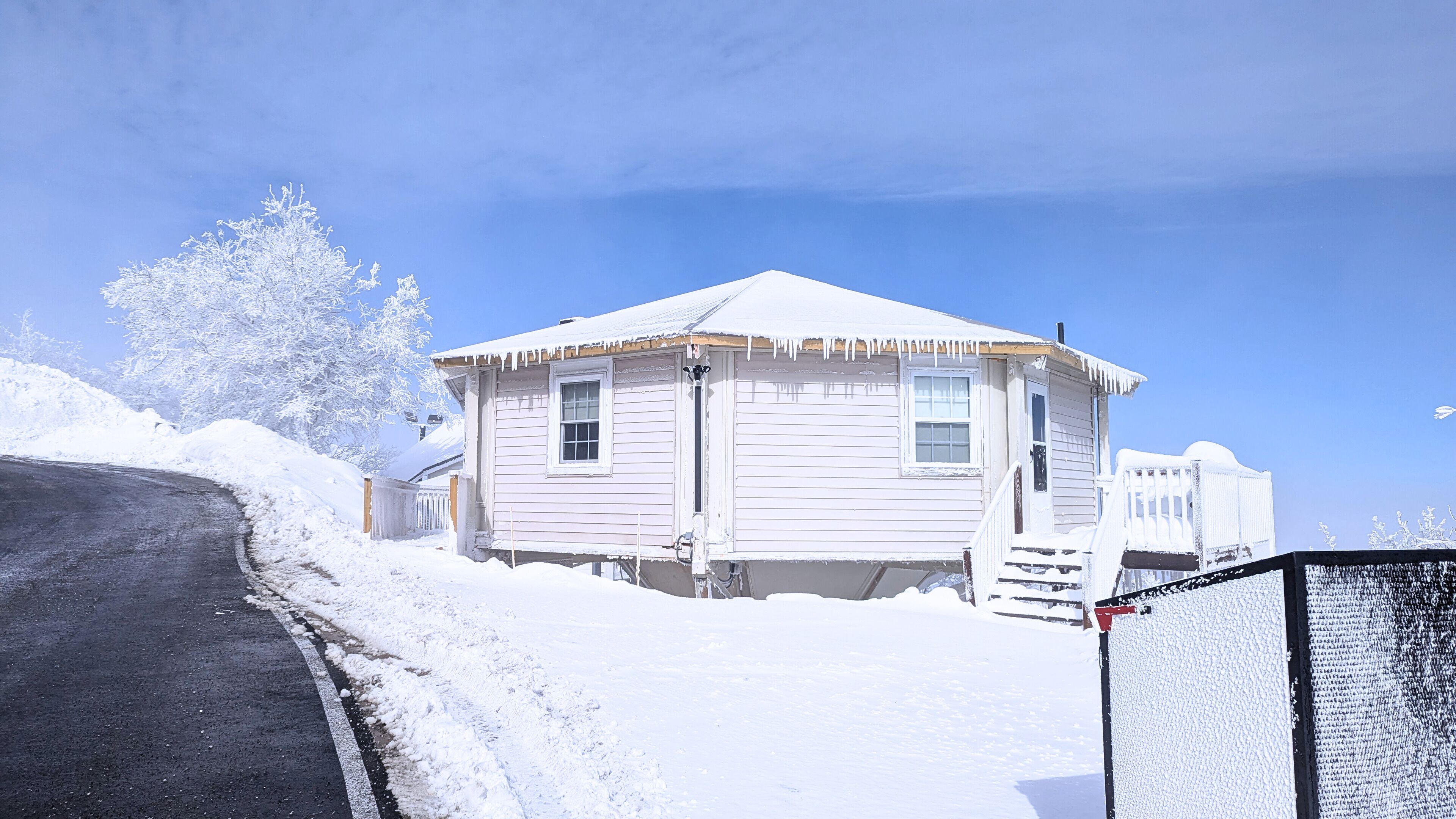 Una casa cubierta de nieve con un porche y un patio cercado.