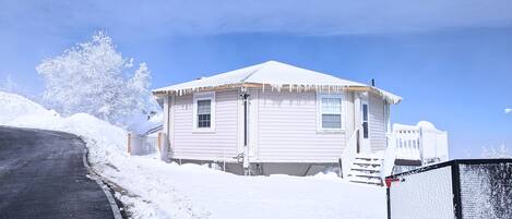 Una casa cubierta de nieve con un porche y un patio cercado.