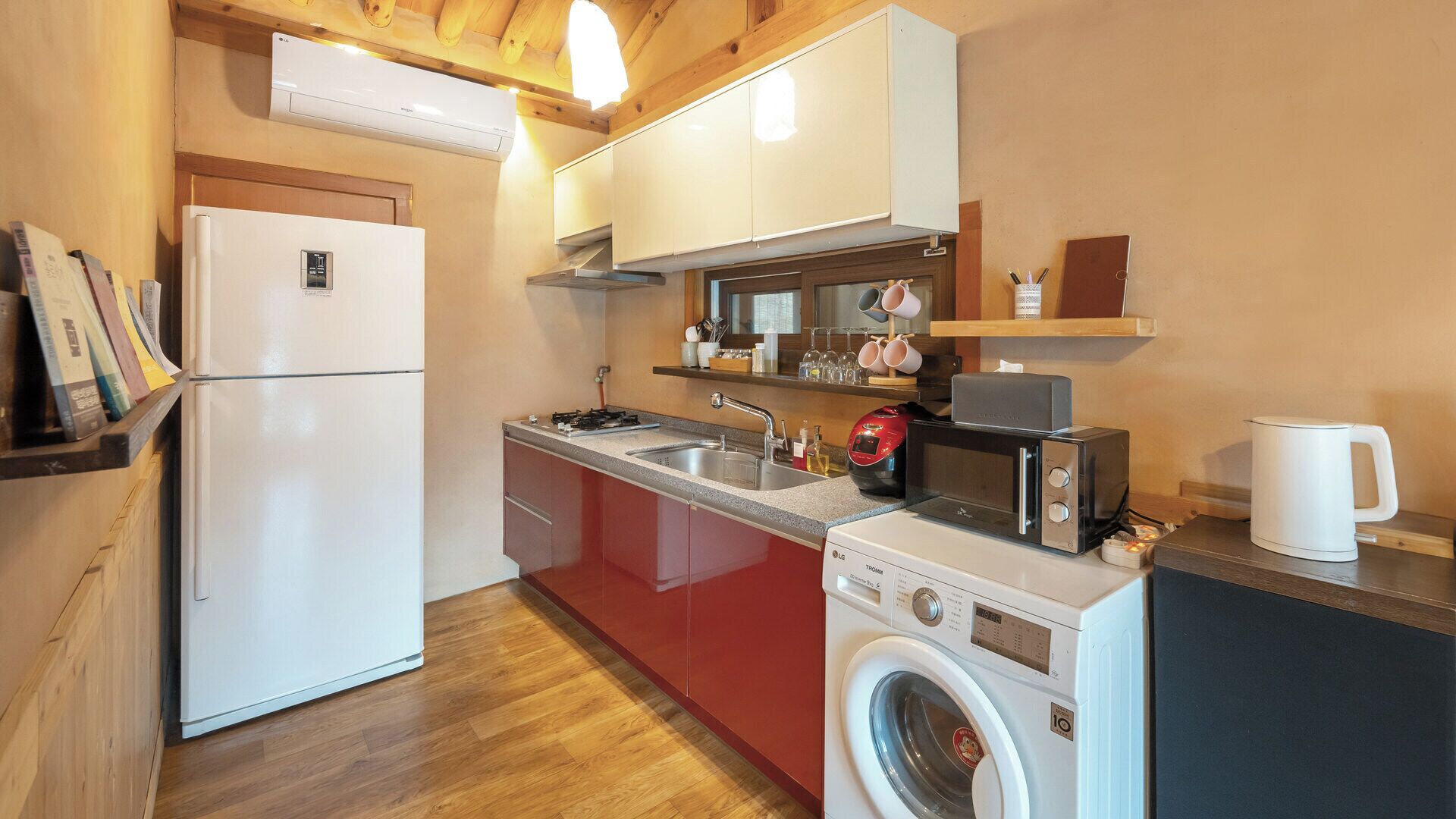 A compact kitchen with a refrigerator, microwave, stove, sink, and washing machine.
