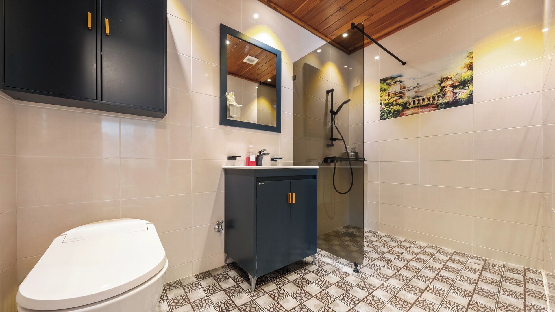 A bathroom with a toilet, dark cabinets, a mirror, and a shower area.