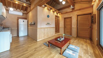 Una cocina acogedora con vigas de madera, un refrigerador blanco y una zona de comedor con mesa y cojines.