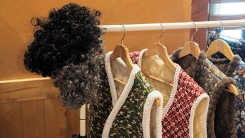 A rack of clothing items, including a variety of sweaters and a wig.