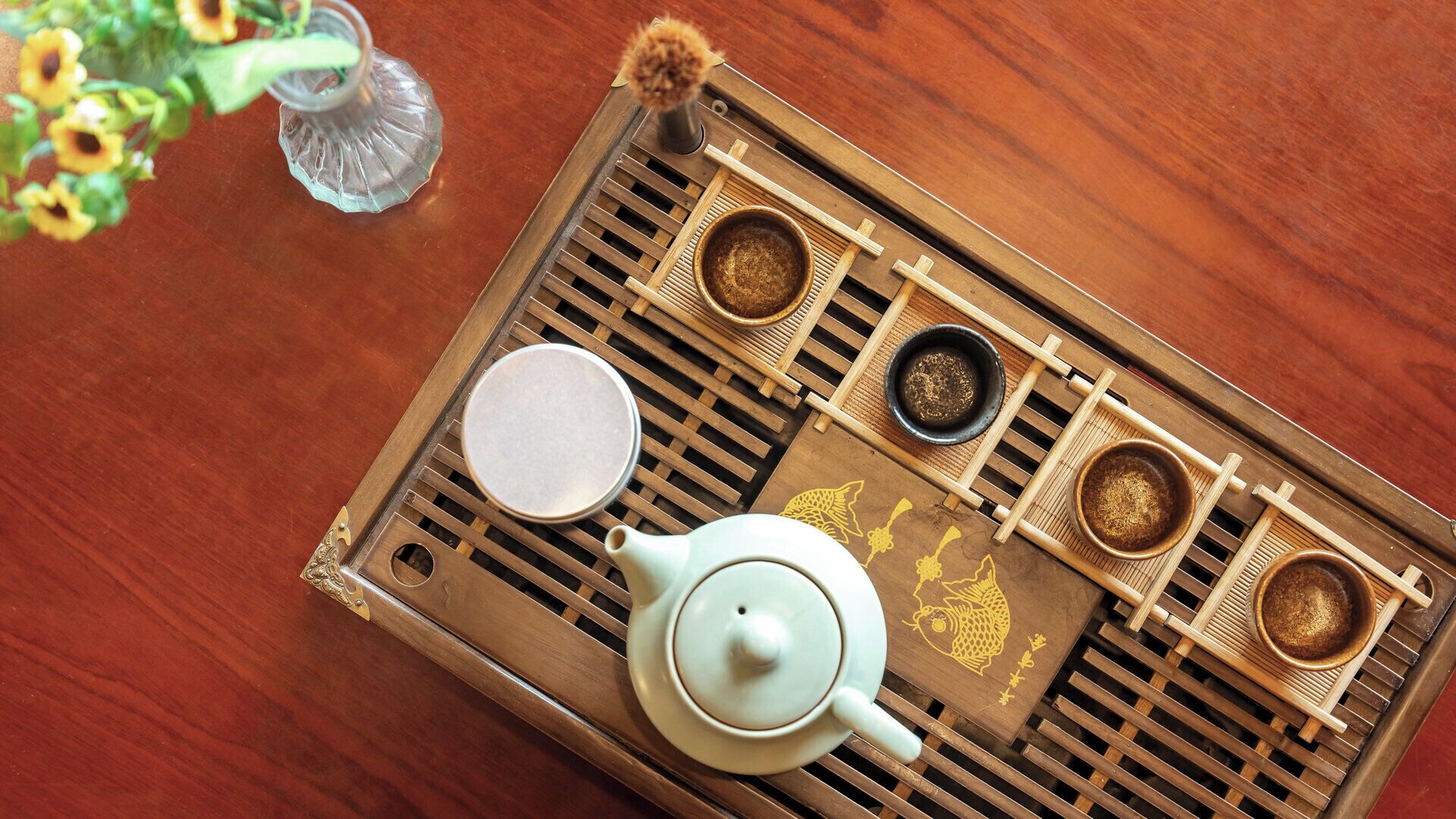 Una bandeja con una tetera, tazas y un cuenco pequeño sobre una superficie de madera.